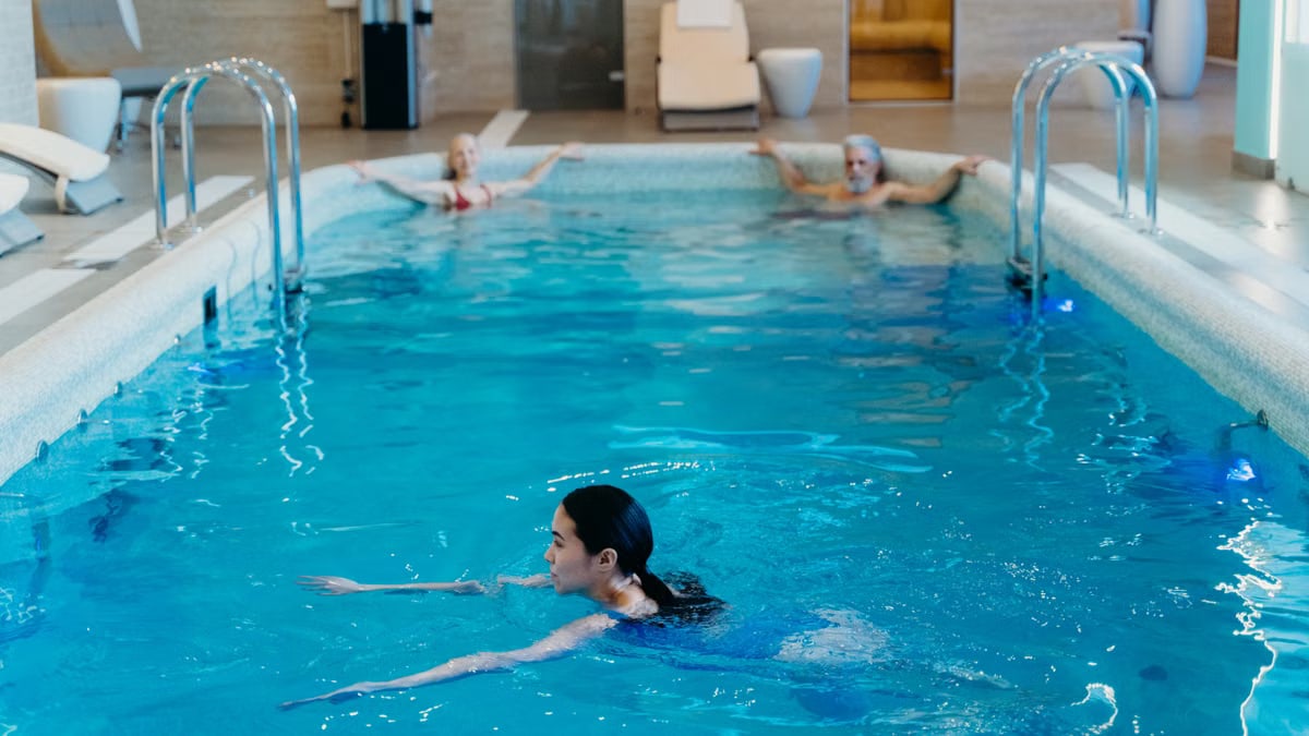 Adults relaxing and swimming in a serene indoor pool setting, perfect for leisure and recreation.